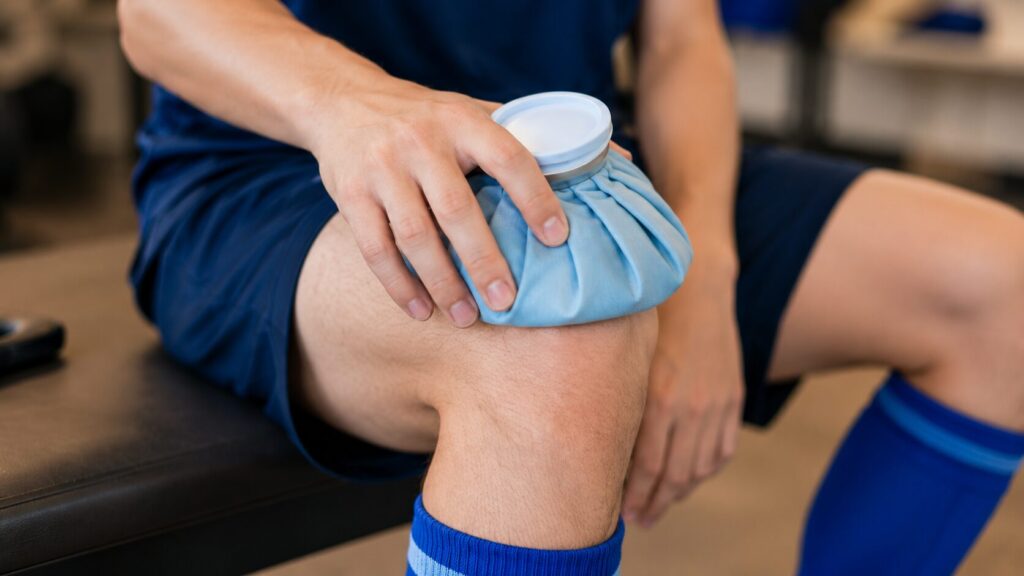 座った状態で膝に布製の氷のうを当て、試合後の患部を冷却している選手