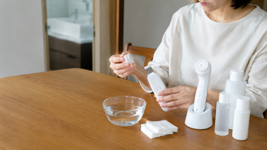 コットンや水、ローション類を用意し、フラット型美容機器のアタッチメントを交換する手元