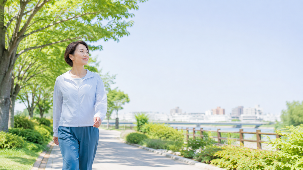 緑の多い遊歩道を自然な姿勢で歩き、日常の運動習慣を取り入れている女性
