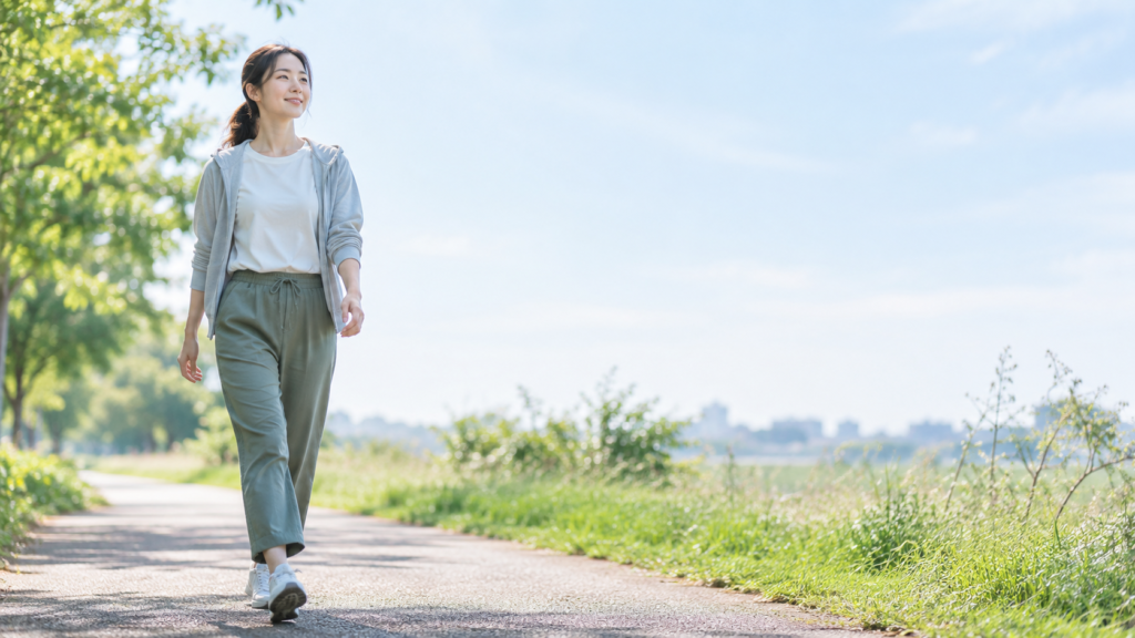 足首の状態を確認しながら、屋外の遊歩道を安定した足取りで歩く女性